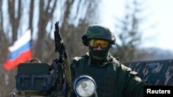 Military personnel, believed to be a Russian serviceman, stands guard on a military vehicle outside the territory of a Ukrainian military unit in the village of Perevalnoye outside Simferopol.