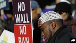 Abdirahman "OJ" Mohamed, dari Seattle, memegang papan bertuliskan "No Wall No Ban" dalam sebuah demonstrasi menentang upaya federal untuk membatasi imigrasi, 6 Desember 2017, di luar gedung pengadilan federal di Seattle. (Foto: dok).