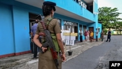 A policewoman keeps watch at a polling station as people queue before casting their ballots to vote in Sri Lanka&#39;s parliamentary election in Colombo.