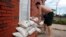 Adam Bazemore places sandbags in the doorways, Sept. 11, 2018, in the Willoughby Spit area of Norfolk, Va., as he makes preparations for Hurricane Florence.