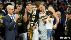 Nikola Jokić i njegova ćerka Ognjena pokazuju prstom na trofej "Bil Rasel", koji je Jokić dobio kao MVP finala plej-ofa (Foto: USA TODAY Sports/Kyle Terada)