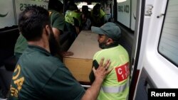 Hospital staff and rescue workers move the body of one of the nine foreign tourists killed by unidentified gunmen near the Nanga Parbat peak, from an ambulance to a hospital morgue in Islamabad, June 23, 2013.