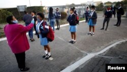 Seorang guru mengukur suhu tubuh siswa ketika sekolah-sekolah mulai dibuka kembali setelah beberapa saat ditutup akibat pandemi Covid-19 di kota Langa di Cape Town, Afrika Selatan, 8 Juni 2020. (REUTERS / Mike Hutchings / File Foto)