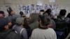 FILE - People examine photos as they search for missing or deceased people on the wall outside the morgue of Al-Mojtahed Hospital in Damascus, Syria, Dec. 11, 2024. 