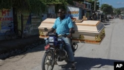 A motorist carries an empty coffin to a morgue for the funeral of a person killed the previous week when a gang attacked the town of Pont-Sonde, Haiti, Monday, Oct. 7, 2024.