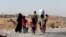 FILE - A displaced family from the minority Yazidi sect walks towards the entrance of Mosul, Aug. 21, 2014.
