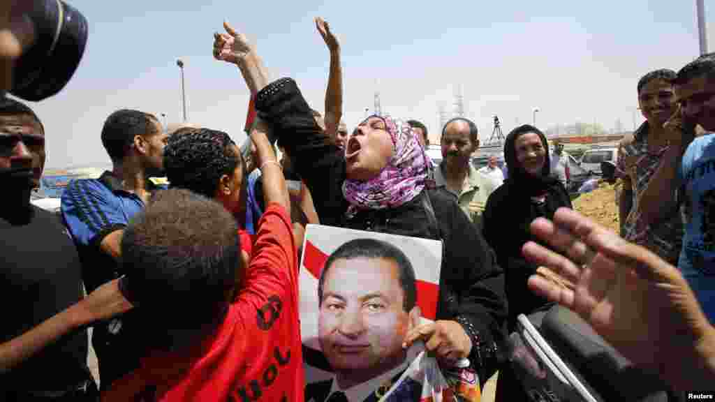 A supporter of former president Hosni Mubarak holds his poster to celebrate as she waits for his release in front of the main gate of Tora prison, Cairo, August 22, 2013.