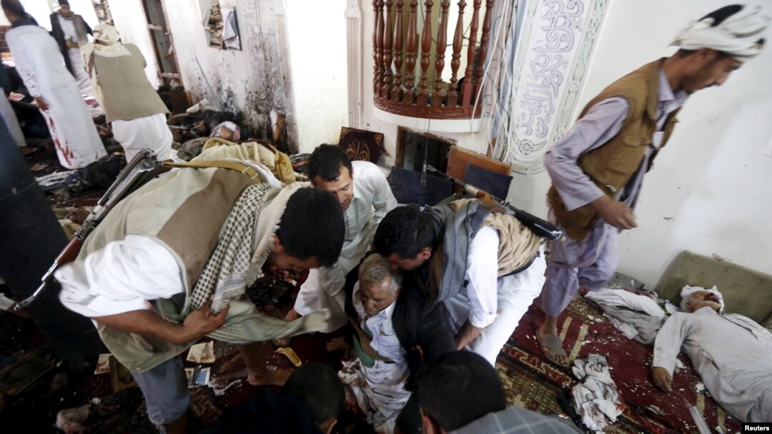 FILE - People help an injured man at the scene of a suicide bombing inside a mosque in Sana'a, Yemen, March 20, 2015.