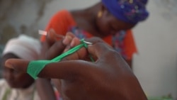 Iness shows how to begin crocheting a basket using strips of plastic (E. Sarai/VOA)