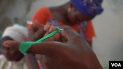 Iness shows how to begin crocheting a basket using strips of plastic (E. Sarai/VOA)
