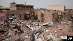 FILE - A man walks by a house hit in fighting in Khartoum, Sudan, an area torn by fighting between the military and the paramilitary Rapid Support Forces, April 25, 2023.