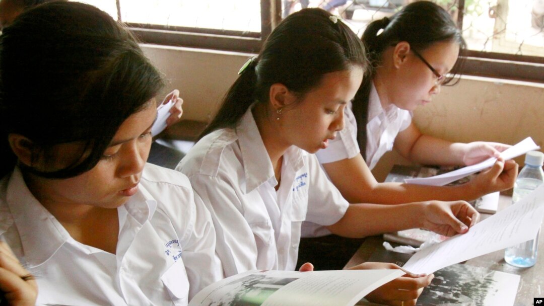 FILE - Students read first-ever Cambodian-authored Khmer Rouge history textbook during its delivery to high school students in Phnom Penh, Cambodia, Oct. 10, 2009.