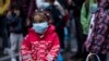 A young girl wearing a mask to prevent the spread of the coronavirus, looks on after refugees and migrants arrived at the port of Piraeus, near Athens, on Monday, May 4, 2020. 