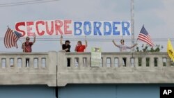 FILE - Demonstrators with signs on an overpass in Indianapolis, Indiana, protest against people who immigrate illegally.