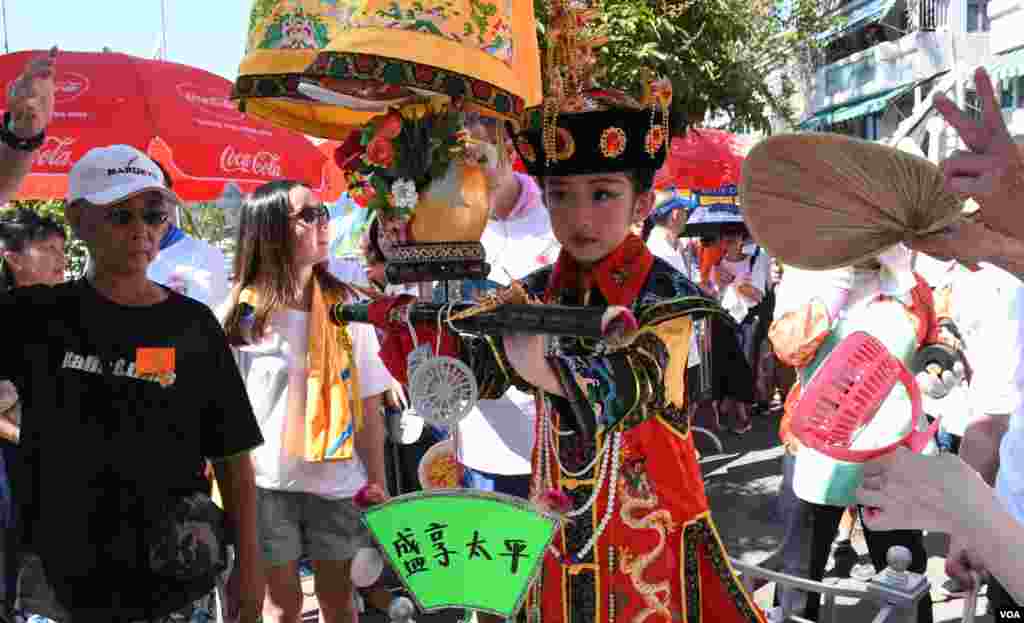 扮演清朝皇后的小女孩身旁有工作人員撥扇降溫。(美國之音湯惠芸拍攝)