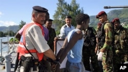 One of the arrested Somali pirates is handcuffed by police upon his arrival in the Port Victoria with the six Seychellois fishermen, 31 Mar 2010