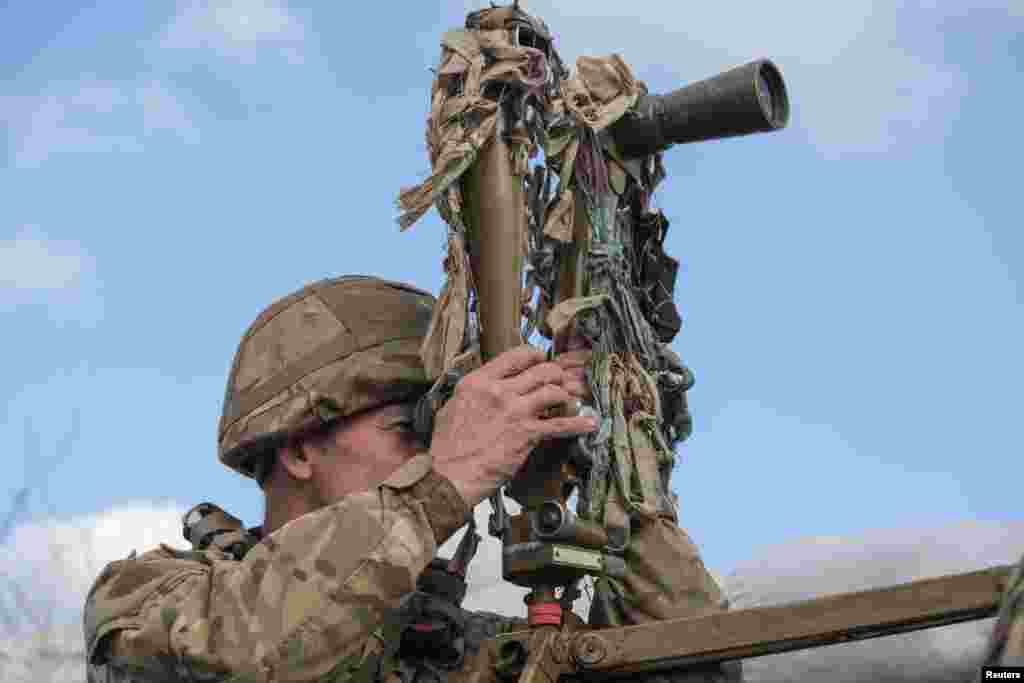 A service member of the Ukrainian armed forces uses a periscope to observe the area along the line of separation near the rebel-controlled city of Donetsk, Ukraine.