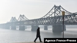 FILE - A man walks near the Friendship Bridge which spans the Yalu River between China and North Korea, in the Chinese border city of Dandong, in China's northeast Liaoning province, Feb. 22, 2019. 