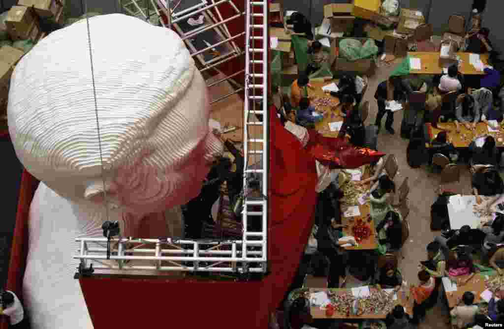 A worker puts the finishing touches to a five-meter (16-feet) tall bust of the late Hong Kong singer and actor Leslie Cheung as origami cranes, folded by fans from around the world in their attempt to set a Guinness world record for the largest number of origami cranes exhibited, are counted at a shopping mall in Hong Kong.