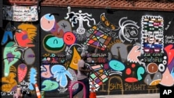 A man walks past a mural in the Harlem neighborhood of New York, Aug. 15, 2024.