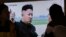 지난달 27일 한국 서울역에서 시민들이 북한 간부 총살에 관한 TV 뉴스를 시청하고 있는 가운데 김정은 북한 국무위원장의 자료사진이 나오고 있다.
