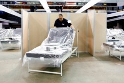 FILE - Robert Reynolds of the California Department of Forestry and Fire Protection moves a bed into position at Sleep Train Arena, which was turned into a field hospital to help deal with the COVID breakout, in Sacramento, Calif., April 18, 2020.