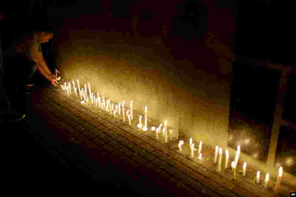 A man places a candle during a vigil outside the Polytechnic School in Rosario, Argentina, Nov. 1, 2017. Five victims killed in the bike path attack near the World Trade Center in New York were part of a group of friends celebrating the 30th anniversary of their graduation from the Polytechnic School of Rosario, Argentina.