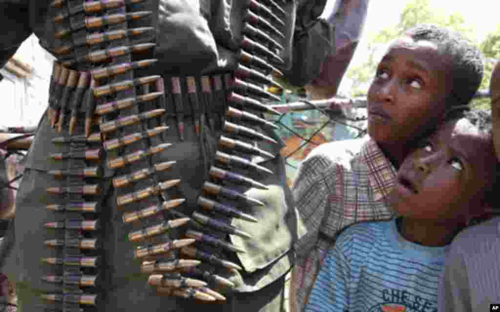 Somali children look at a Transitional Federal Government (TFG) soldier carrying a belt of machine gun ammunition during patrol along the Indian Ocean coastline in Burgabo, south of Kismayu in Somalia December 14, 2011. REUTERS/Noor Khamis (KENYA - Tags: 