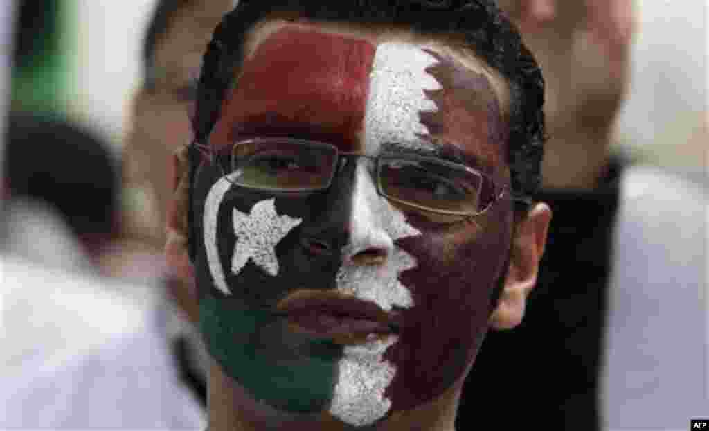 A Libyan university student with his face painted with the pre-Gadhfi flag and the Qatari flag, takes part in an anti- Gadhafi demonstration for students of the faculty of medicine of the University of Qar Younis, in Benghazi, Libya Sunday, March 13, 2011