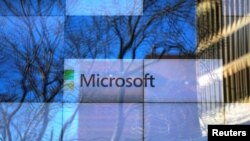 FILE - An advertisement is played on a set of large screens at the Microsoft office in Cambridge, Massachusetts, U.S.