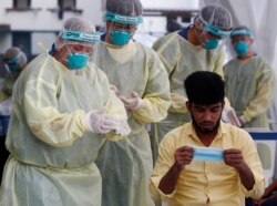 FILE - Medical workers prepare to perform a nose swab on a migrant worker at a dormitory, amid the coronavirus disease (COVID-19) outbreak in Singapore, May 15, 2020.