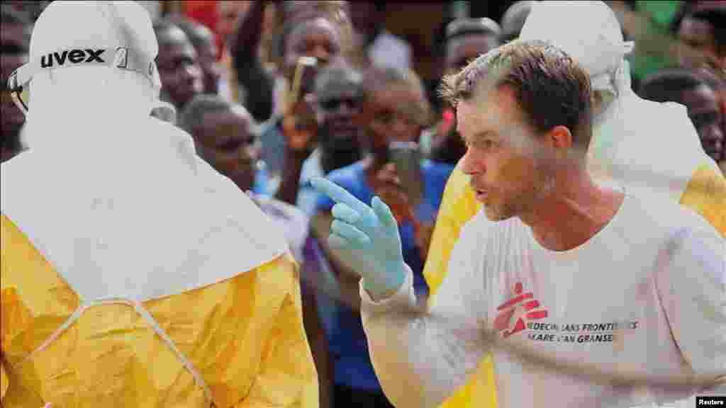 A doctor speaks as health workers surround an Ebola patient who escaped from quarantine from the Elwa Hospital, Paynesville, Liberia, Sept. 1, 2014.