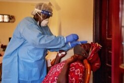 FILE - A member of South Sudanese Ministry of Health Rapid Response Team takes a nasal sample from a woman at her home in Juba, South Sudan, April 14, 2020.