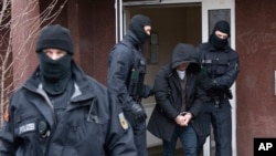 Police officers escort a suspect during a raid in Berlin, Germany, March 3, 2020.