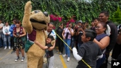 Wisin, el “perrito luchador”, es abrazado por un niño mientras saluda a los fanáticos en un evento de lucha libre en el Instituto de la Juventud, en la Ciudad de México, el 25 de julio de 2024.