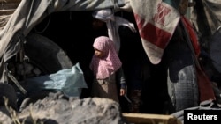 FILE - A girl stands outside her family's hut at a camp for internally displaced people on the outskirts of Sanaa, Yemen, March 1, 2021.