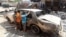 Iraqi children inspect a burned out car at the site of a car bomb attack that exploded the previous day in a commercial street of Baghdad's eastern neighborhood of Mashtal, Sept.16, 2013.
