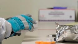 Pharmacist Michael Witte opens a frozen package of the potential vaccine for COVID-19 on the first day of a first-stage safety study clinical trial, at the Kaiser Permanente Washington Health Research Institute in Seattle. Washington, March 16, 2020.