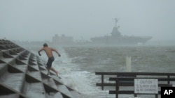 A man jumps from a wave as Hurricane Hanna begins to make landfall, Saturday, July 25, 2020, in Corpus Christi, Texas. The National Hurricane Center said Saturday morning that Hanna's maximum sustained winds had increased and that it was expected…