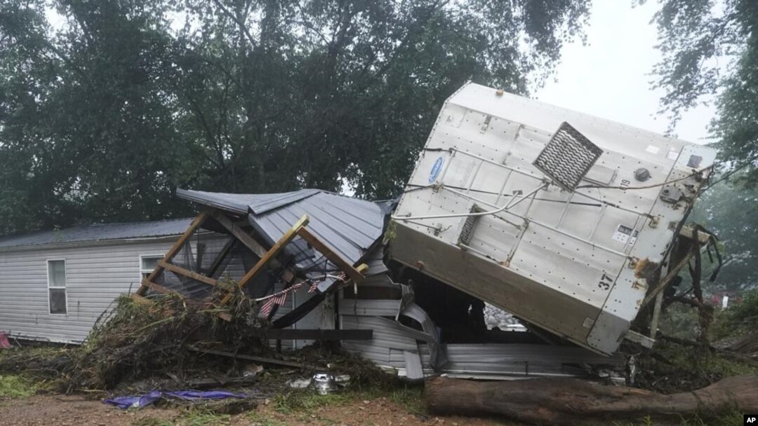 Sebuah rumah mobil dan sebuah truk trailer terlihat berada di dekat sungai Minggu, 22 Agustus 2021, setelahhanyut oleh air banjir sehari sebelumnya di Tennessee. (Foto: AP)
