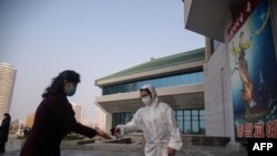 북한 평양의 한 공연장에서 신종 코로나바이러스 방역을 위해 입장객들의 체온을 재고 손을 소독하고 있다.