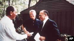 A Camp David, en septembre 1978, Jimmy Carter sourit tandis que le président égyptien Anouar el-Sadate (à g.) et le Premier ministre israélien Menachem Begin se donnent la main