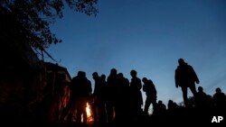 Migrants warm up by fire while waiting to enter a camp in Spielfeld, Austria, Sunday, Oct. 25, 2015.