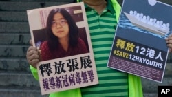 A pro-democracy activist holds placards with the picture of Chinese citizen journalist Zhang Zhan outside the Chinese central government's liaison office, in Hong Kong, Monday, Dec. 28, 2020. 