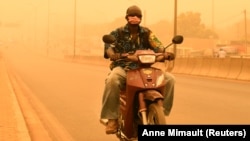 Un homme conduit sa moto pendant une tempête de sable au milieu de la propagation de la maladie à coronavirus (COVID-19) à Ouagadougou, au Burkina Faso, le 15 avril 2020. (Photo: REUTERS/Anne Mimault)