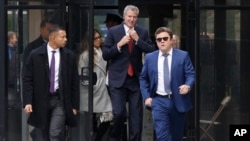 FILE - New York Mayor Bill de Blasio, center, adjusts his tie as he arrives at City Hall in New York, before a news conference, Nov. 8, 2017.