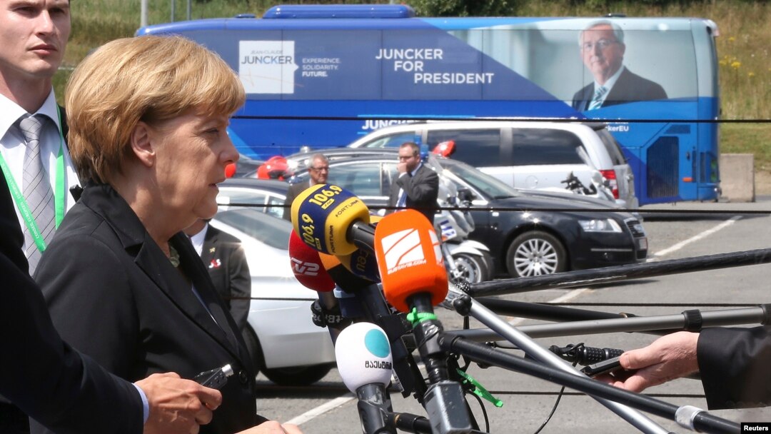 Germany's Chancellor Angela Merkel speaks near a promotional campaign bus of candidate for the European Commission presidency Jean-Claude Juncker as she arrives at an European People's Party meeting in Kortrijk, June 26, 2014.