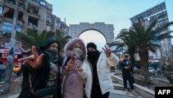 TOPSHOT - Local residents cheer as they gather on a street in the Damascus suburb of Jaramana on December 8, 2024.