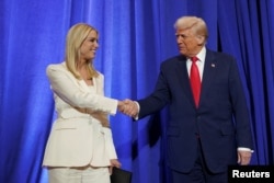 资料照片：美国总统特朗普访问位于华盛顿的司法部总部并对员工发表讲话期间与司法部长邦迪握手。(2025年3月14日)