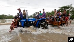 Warga mengarungi banjir yang deras dengan naik traktor di sebuah jalan layang di La Paz, provinsi Tarlac di Filipina utara (20/10). (AP/Bullit Marquez)